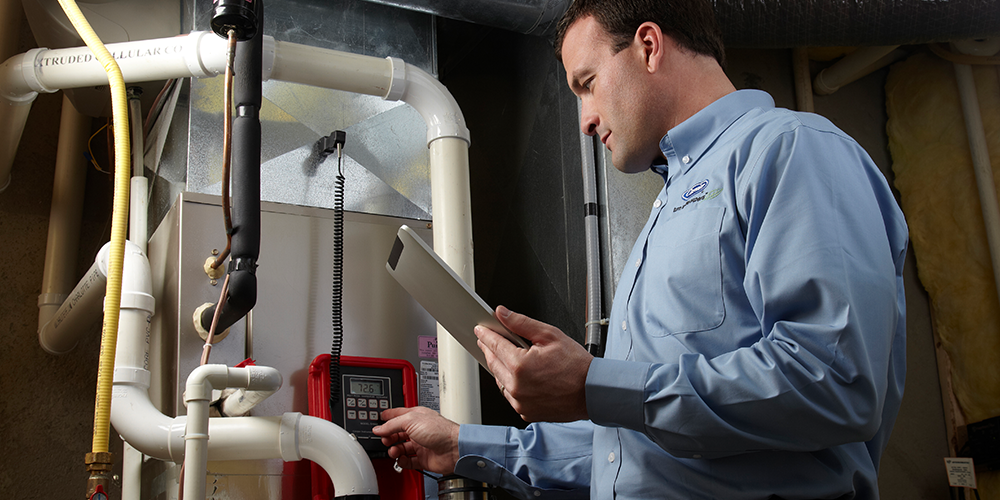 Tech in blue shirt examines a furnace after the heat goes out.