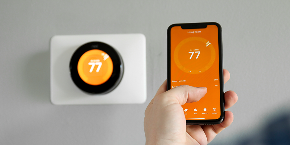 Homeowner uses smartphone to control temperature of their Wi-Fi-enabled thermostat.