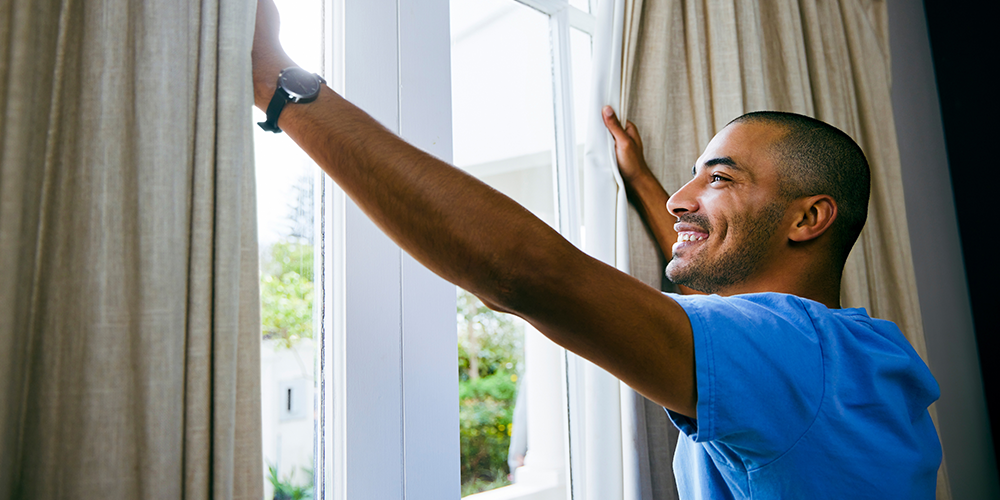 Happy homeowner opens window after learning how to keep your house cool